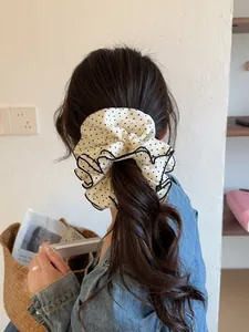 Polka dot oversized hair scrunchie with layered ruffles worn on wavy brown hair
