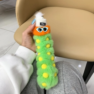 Detail of green plush caterpillar keychain with white knit hat and blue sunglasses