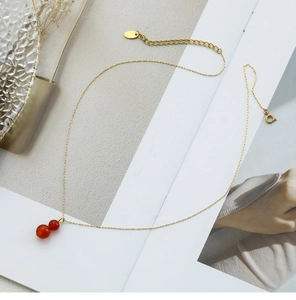 Close-up of gold chain necklace with double red agate gourd-shaped bead pendants