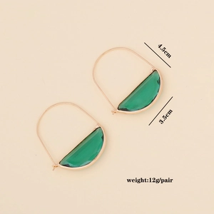 Detail view of green geometric glass earrings with size and weight text on beige background