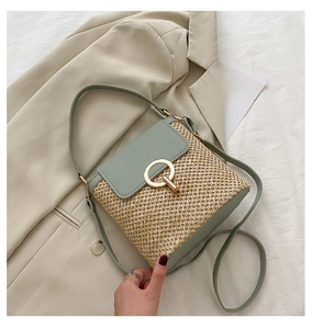 Close-up of straw beach bag with green faux leather flap and gold metal buckle