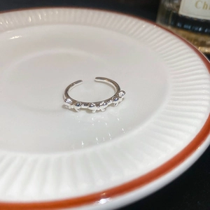 Detailed view of silver bow-shaped open ring placed on a minimalist ceramic plate