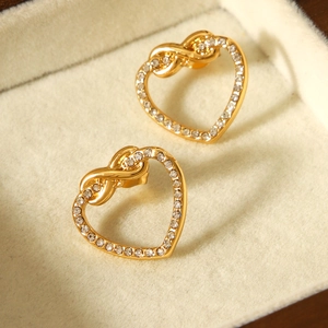 Close-up of gold heart earrings with sparkling rhinestones in a velvet jewelry box
