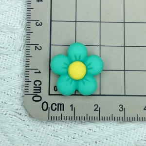 Close-up of a 1.8cm green resin flower bead on a metric ruler for size reference