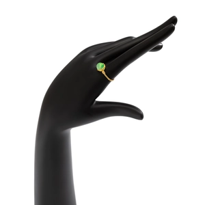Detail of handmade wire wrapped ring with green bead on black display stand