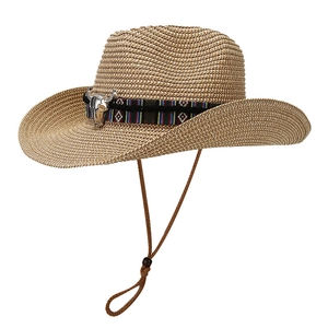 Western straw cowboy hat with ethnic ribbon and bull metal ornament on white background