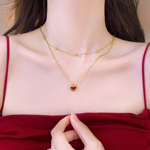 Double-layered golden stainless steel necklace with a red heart pendant on a female model