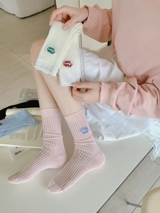 Detail of pink knitted cotton socks with white letter embroidery and ribbed texture