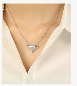 Detail of silver triangle pendant necklace on snake chain with high polish finish