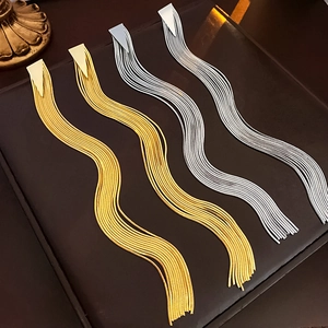 Detail of gold and silver snake chain fringe earrings with triangle studs on a tray