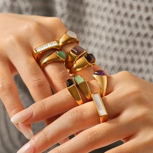 Close-up of vintage stainless steel gold rings with teardrop white shell and natural stones