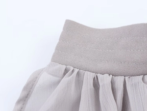 Detailed close-up showing grey elastic waistband and pleated chiffon fabric texture