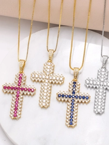 Détail de pendentifs croix en zircons colorés sur des chaînes vénitiennes or et argent