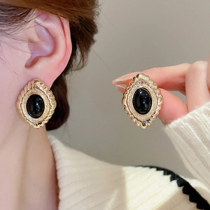 Detail of vintage oval black stone earrings with textured gold border in a French style