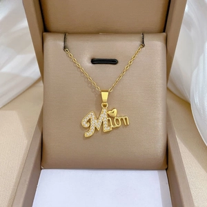 Detailed macro view of the gold Mama letter pendant with sparkling crystals in a gift box