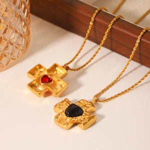 Detail of hammered gold cross pendants with inlaid red and black heart-shaped gemstones