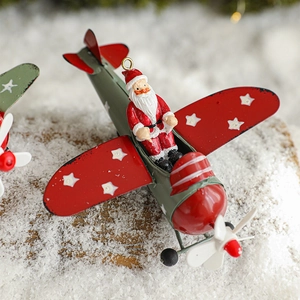 Vintage metal Christmas plane ornament with Santa Claus figure on snowy wooden background