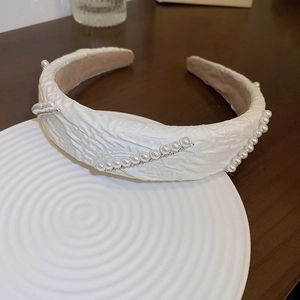 Detail of cream pleated fabric headband with white pearls and silver rhinestones