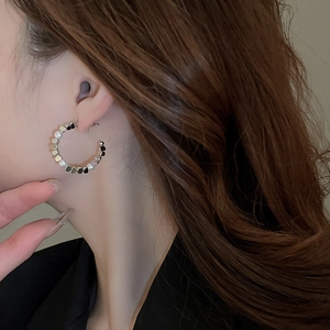 Close-up of C-shaped earrings with silver metal sequins and white round pearls