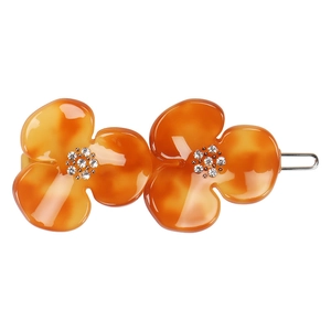 Detail of amber tortoiseshell hair clip with floral resin design and sparkling rhinestones