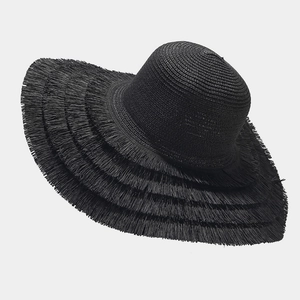 Close-up of black wide brim straw hat featuring layered raw fringe edges and woven texture