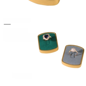 Detail of luxury metal ring display stands with emerald green and grey velvet padding