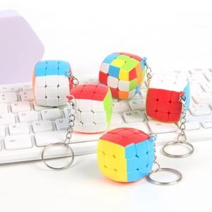 Mini 3x3 colorful speed cube keychains displayed on a white computer keyboard