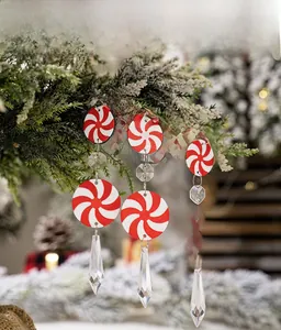 Close-up of red and white peppermint candy ornaments with crystals on a snowy tree