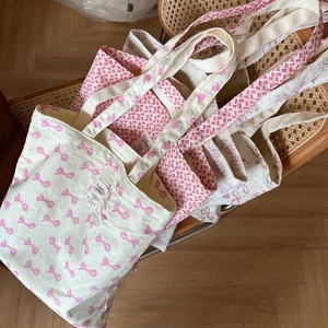 Détail de sacs cabas en toile de coton avec motifs nœuds roses et étiquettes décoratives