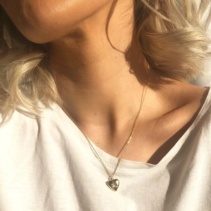 Close-up of a golden heart-shaped locket necklace worn on a woman's neck for gift