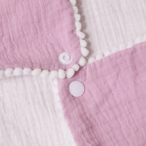 Pink checkered cotton muslin baby bib with pom-pom trim and white snap fasteners