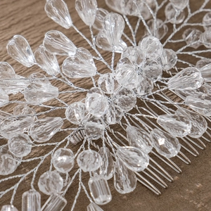 Exquisite bridal hair comb with crystal beads and silver wire on wooden surface
