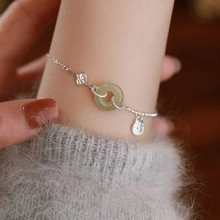 Close-up of silver double-layered bracelet with green moonstone heart and cloud charms