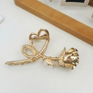Macro view of gold rose and heart metal hair claw clip with detailed floral textures