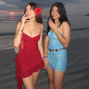 Detail showing red sequined mini dress with ruffles and blue printed tube dress on beach