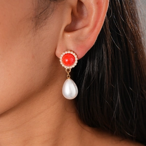 Detail of vintage red stone and pearl drop earring worn on ear with gold metal accents
