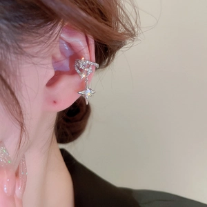 Close-up of asymmetric silver star ear cuff with zircon cross pendant on model