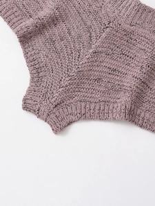 Dettaglio della trama a maglia grossa e dell'orlo su un maglione rosa polvere