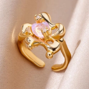 Detailed close-up of a golden flower ring with pink heart stone and zircon on beige silk