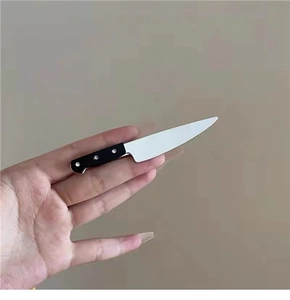 Macro view of a miniature dagger hair clip with black handle and silver metallic blade