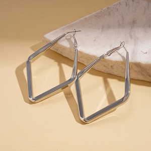 Macro view of geometric diamond shaped silver hoop earrings on a marble stone base