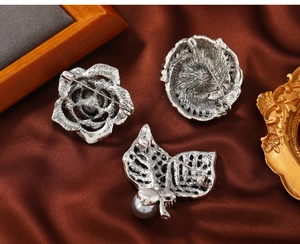 Detailed back view of vintage silver brooches with secure metal pins on brown silk