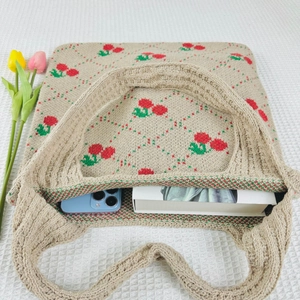 Close-up of beige knit tote bag with cherry flower patterns showing spacious interior