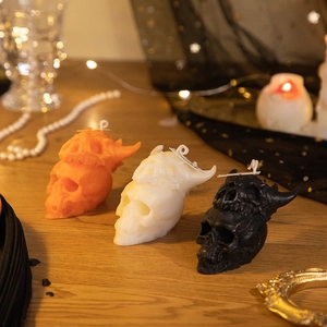 Skull candles in orange white and black displayed on a wooden table with gothic decor