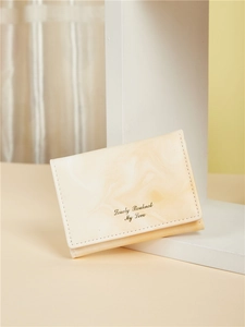 Detail of slim cream orange marble pattern trifold wallet with gold lettering
