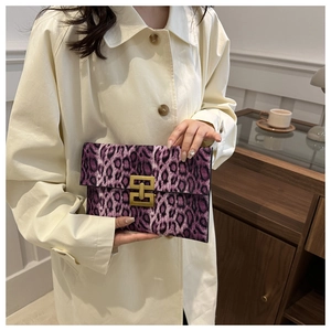 Detail of purple leopard print clutch bag featuring a gold geometric metal buckle closure