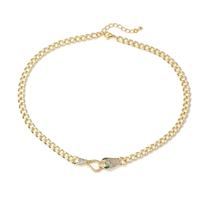 Macro detail of 18K gold snake necklace featuring green stone eyes and cubic zirconia