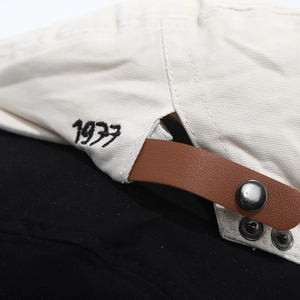 Macro detail of 1977 embroidery and brown leather strap with silver metal buckles