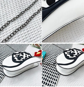 Detail of white cow print cowboy hat bag with black metal chain and stitching texture