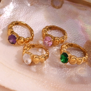 Detail of 18K gold plated beaded rings with colorful oval gemstones on shell